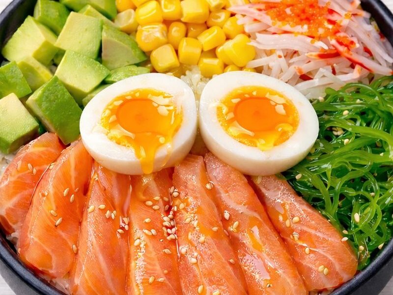 A salmon poke bowl with avocado, corn, crab stick and soft-boiled egg